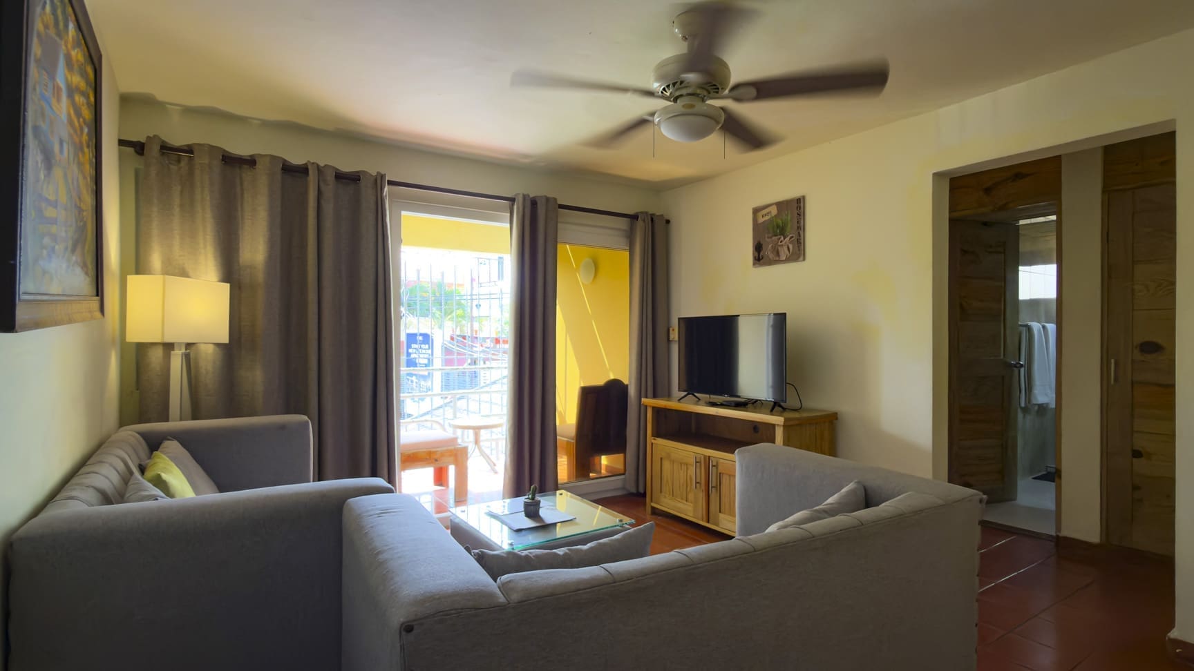 buyDRproperty Cozy living room with gray sectional sofa, glass coffee table, and TV. Sosua Real Estate
