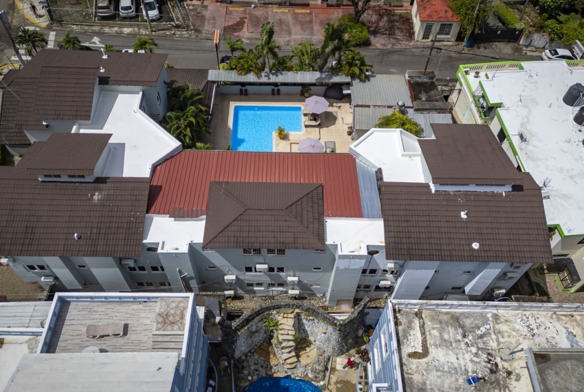 buyDRproperty Aerial view of a hotel complex with a blue pool and brown rooftops. Sosua Real Estate