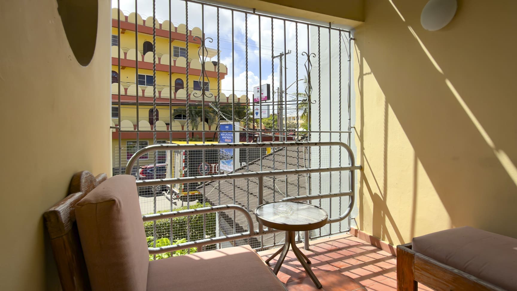 buyDRproperty Balcony with chair and table overlooking a colorful building in a tropical city. Sosua Real Estate