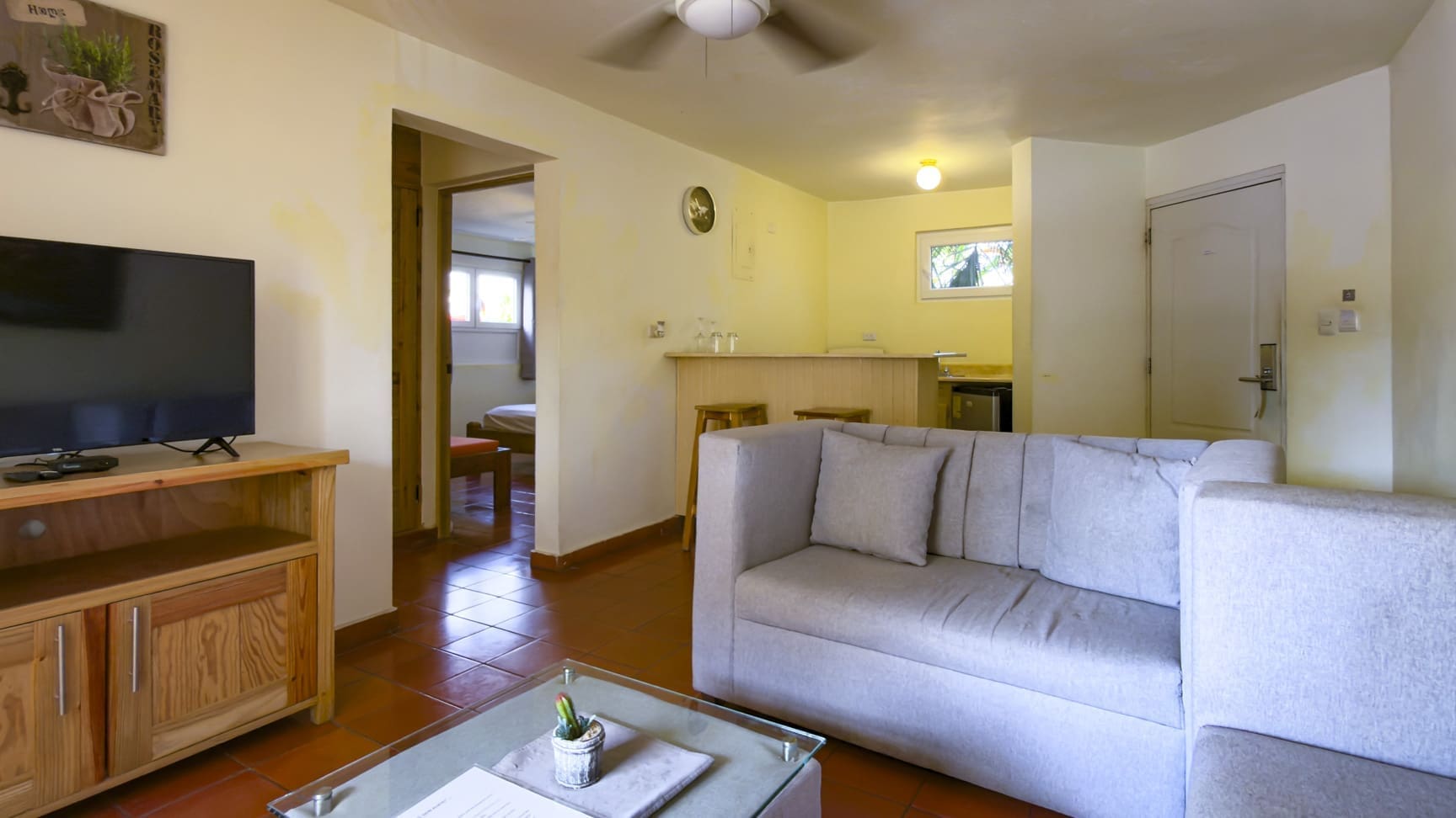 buyDRproperty Living room with sofa, TV, and kitchen counter, opening to a bedroom. Sosua Real Estate