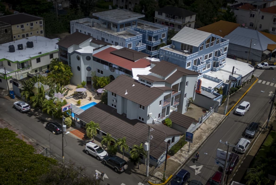 buyDRproperty Aerial view of a residential neighborhood with multi-story buildings and cars on the street. Sosua Real Estate