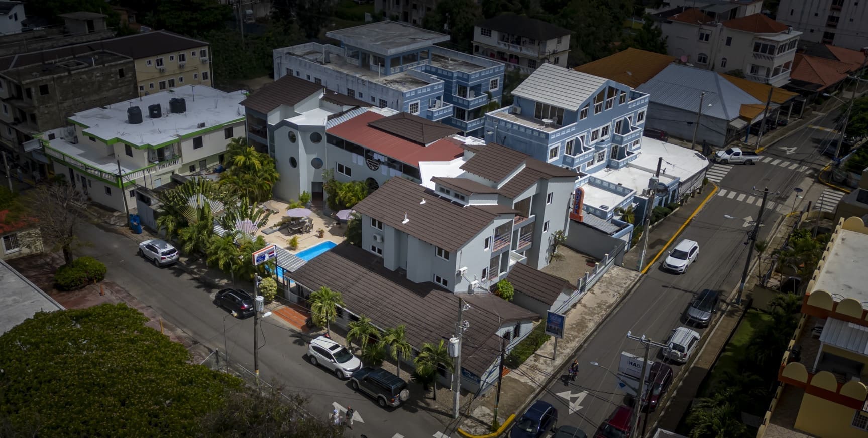 buyDRproperty Aerial view of a residential neighborhood with multi-story buildings and cars on the street. Sosua Real Estate