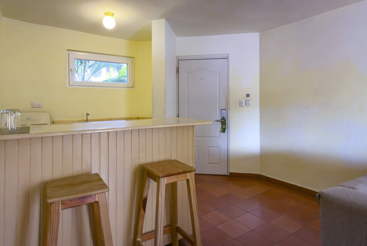 buyDRproperty Hotel room kitchenette with a bar, stools, and a closed door Sosua Real Estate