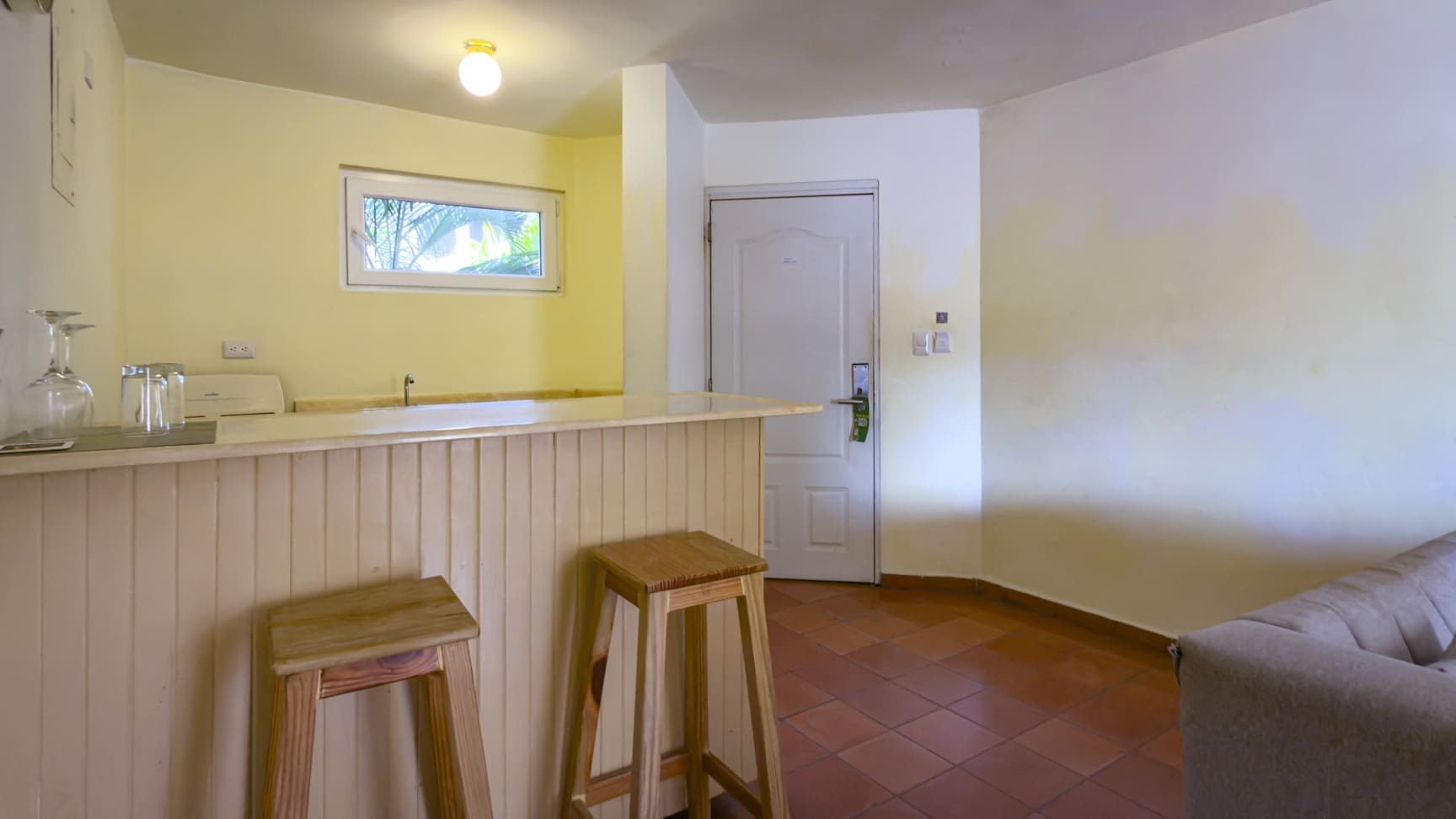 buyDRproperty Hotel room kitchenette with a bar, stools, and a closed door Sosua Real Estate