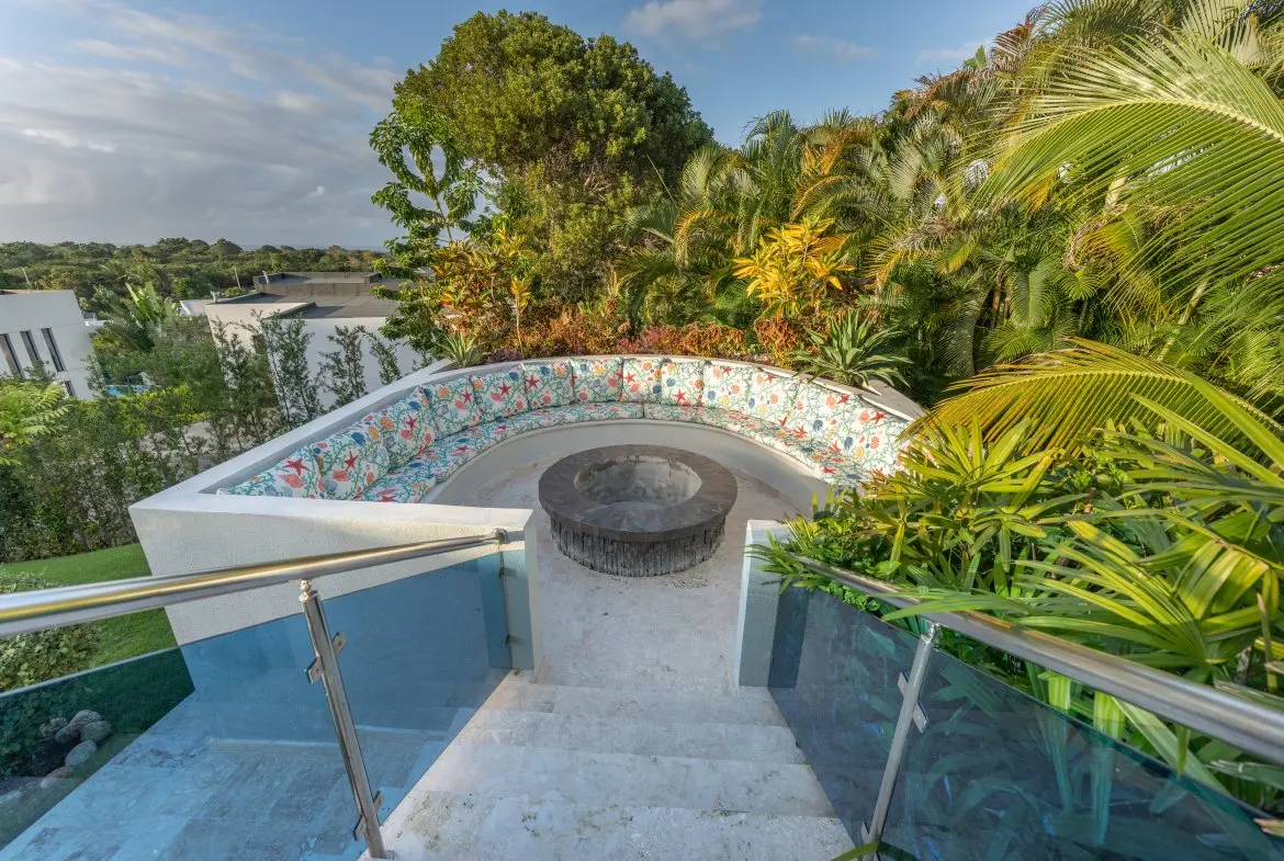 buyDRproperty Curved outdoor seating area with a fire pit surrounded by lush tropical plants. Sosua Real Estate