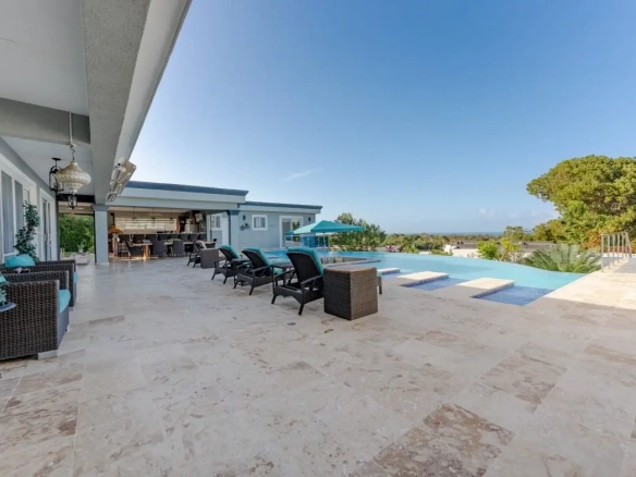 buyDRproperty Luxury infinity pool with lounge chairs and ocean view from patio Sosua Real Estate