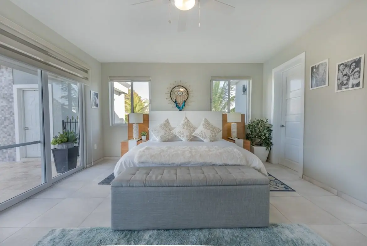 buyDRproperty Modern bedroom with king-size bed, large windows, and a grey storage bench. Sosua Real Estate