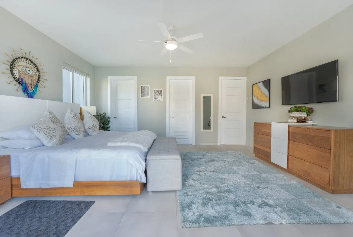 buyDRproperty Spacious master bedroom with king-size bed, modern furniture, and ceiling fan. Sosua Real Estate