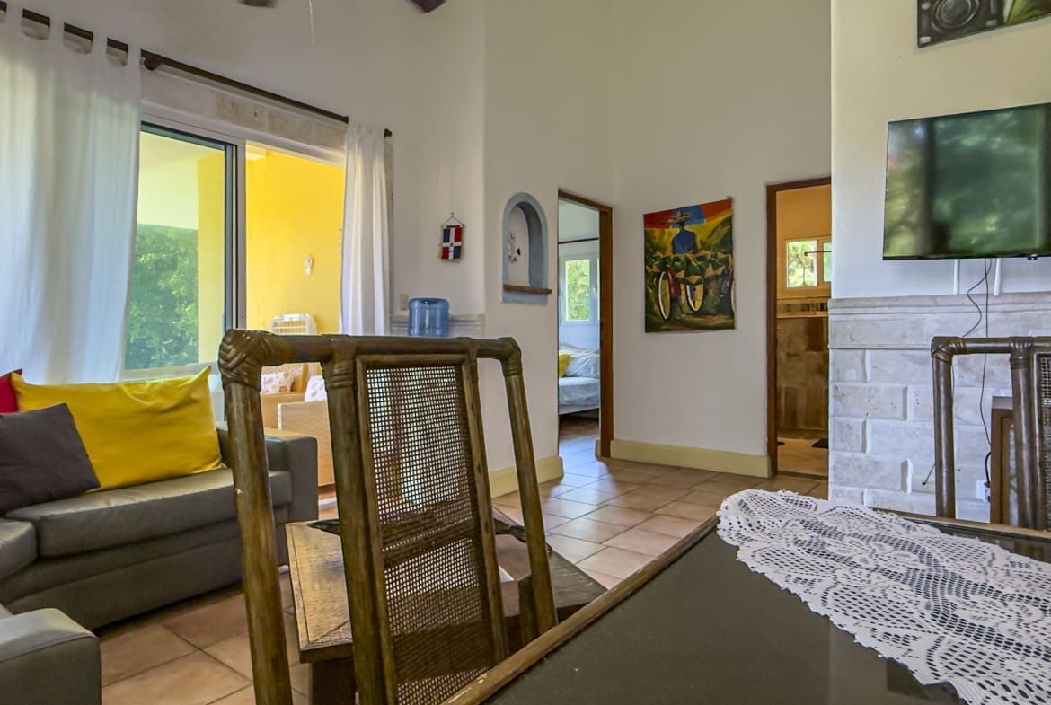 buyDRproperty Living room with sofa, dining table, and open doorway to a bedroom. Sosua Real Estate