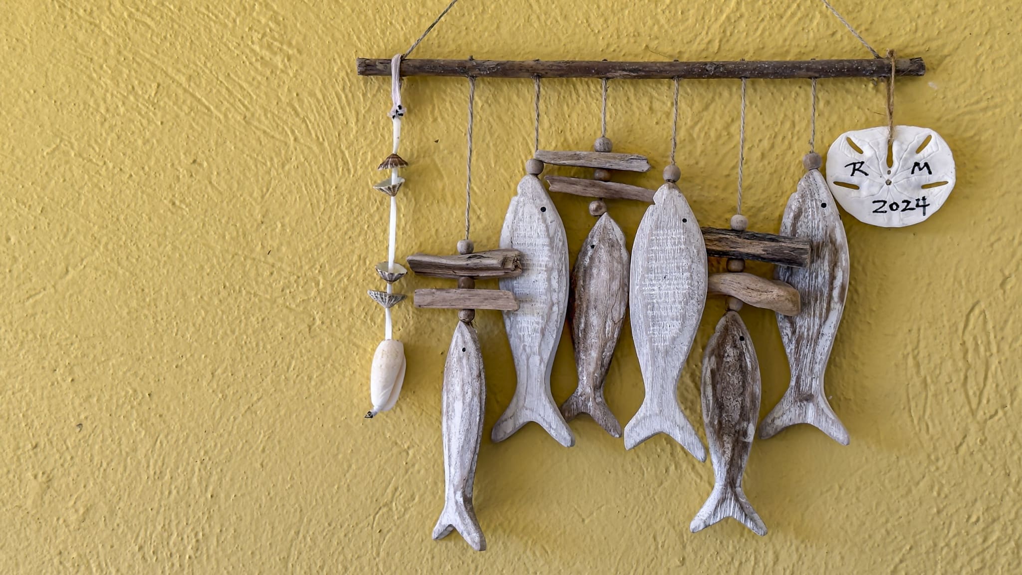 buyDRproperty Handmade wooden fish mobile with shells and sand dollar on yellow wall Sosua Real Estate