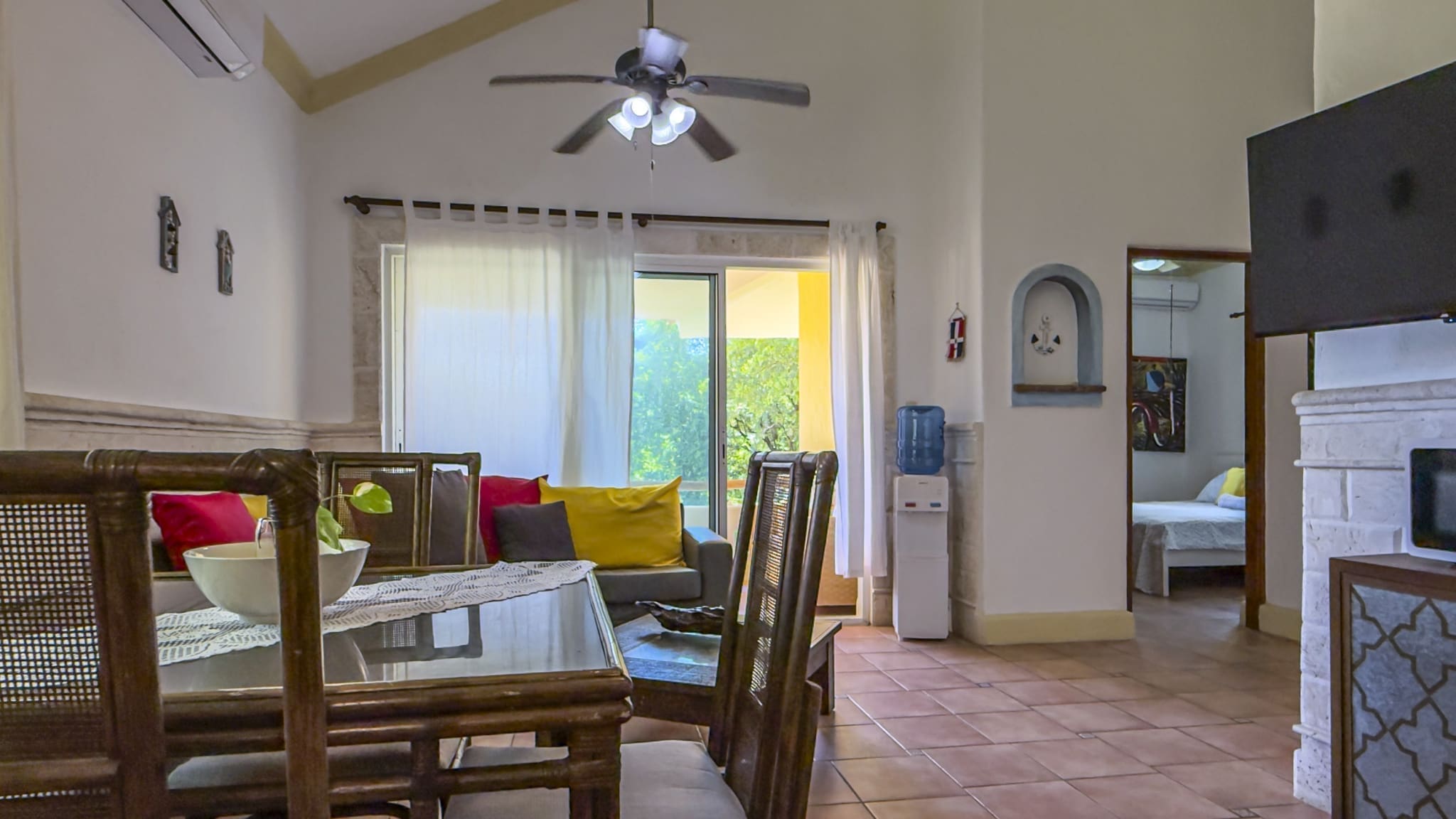buyDRproperty Dining area with rattan chairs and table in a bright, open-plan living space with a sofa and sliding glass doors. Sosua Real Estate