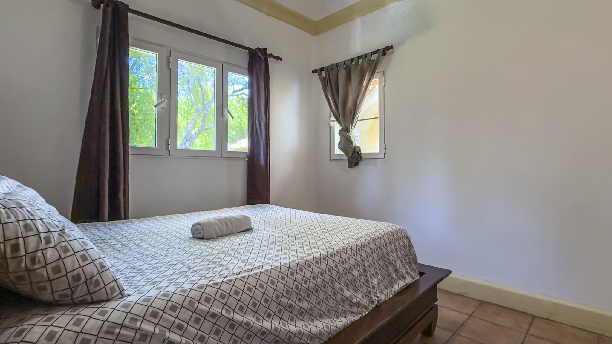 buyDRproperty Cozy bedroom with a bed, white walls, and a large window overlooking green trees. Sosua Real Estate