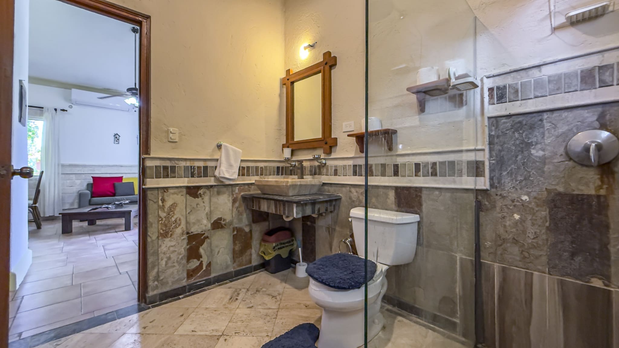 buyDRproperty Rustic bathroom with stone sink, toilet, and glass shower stall Sosua Real Estate