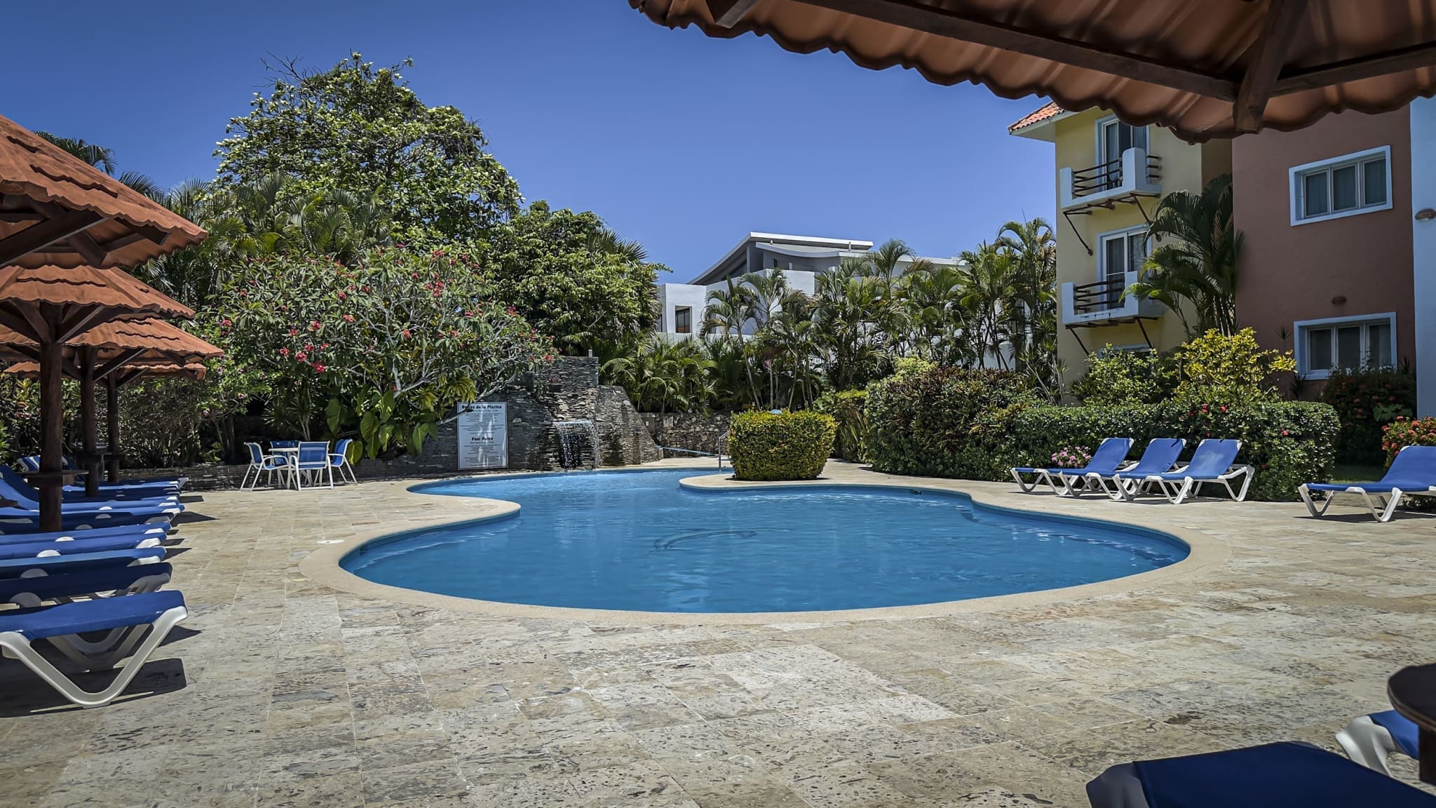 buyDRproperty Swimming pool surrounded by lounge chairs under umbrellas at a resort Sosua Real Estate