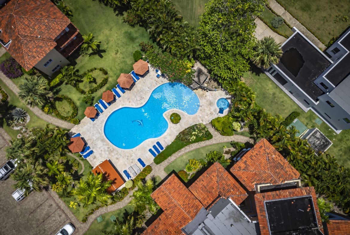 buyDRproperty Aerial view of a resort pool with lounge chairs, umbrellas, and surrounding buildings. Sosua Real Estate