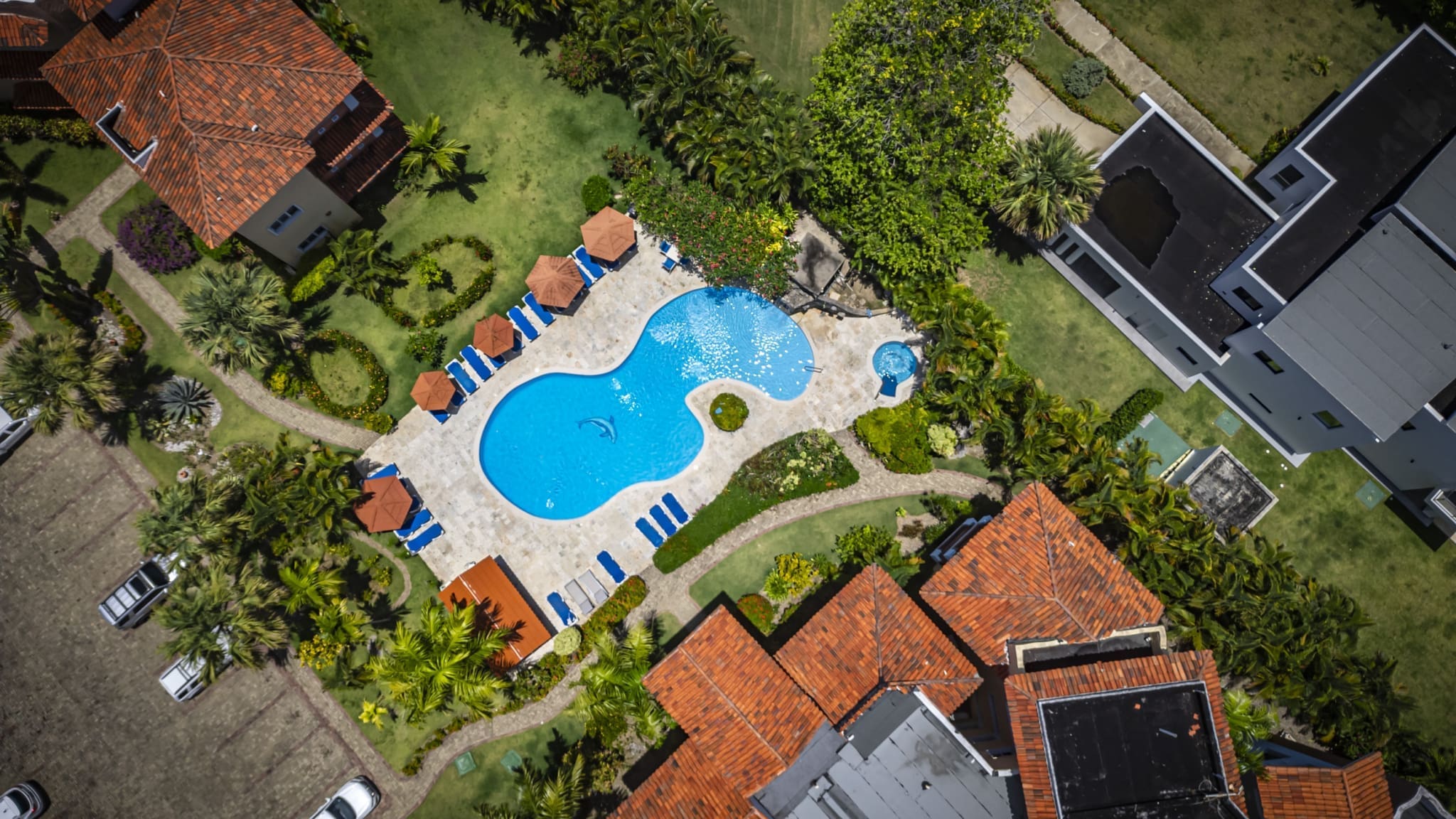 buyDRproperty Aerial view of a resort pool with lounge chairs, umbrellas, and surrounding buildings. Sosua Real Estate