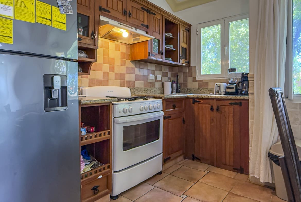 Cozy kitchen with a stainless refrigerator, white oven, granite counters, and warm wooden cabinets under a tiled backsplash.