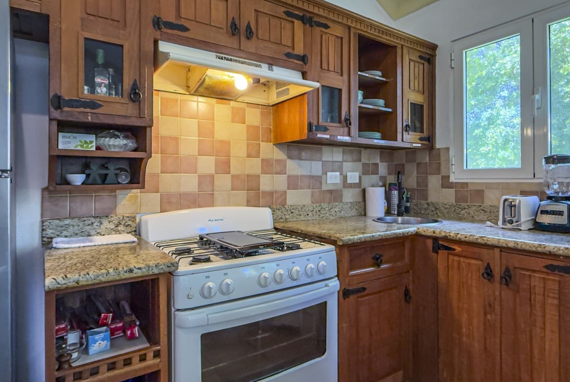 buyDRproperty Cozy kitchen with wooden cabinets, white gas stove, and window view Sosua Real Estate