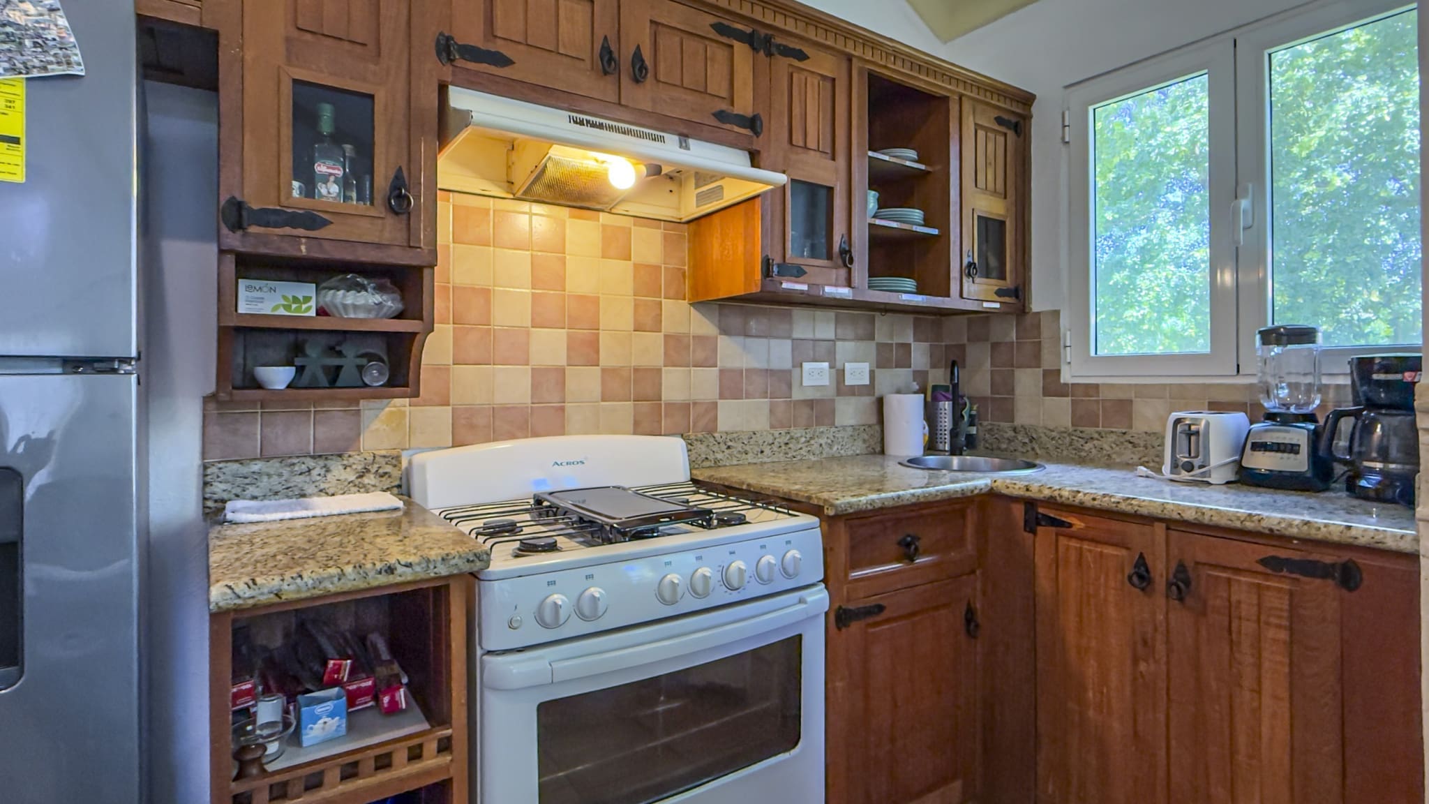buyDRproperty Cozy kitchen with wooden cabinets, white gas stove, and window view Sosua Real Estate
