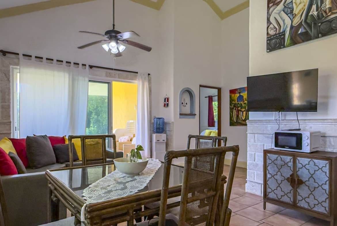 buyDRproperty Dining area with rattan chairs and table, living room with sofa, and TV. Sosua Real Estate