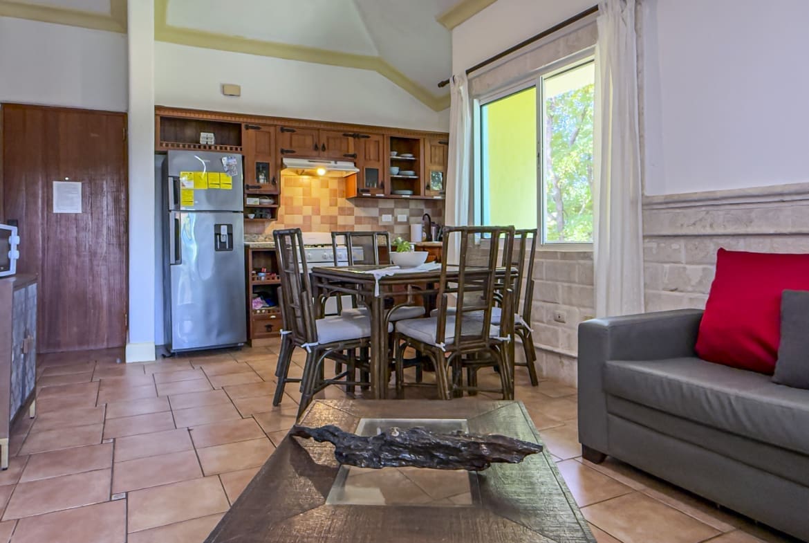 buyDRproperty Cozy dining area and kitchen with stainless steel refrigerator and wooden furniture. Sosua Real Estate
