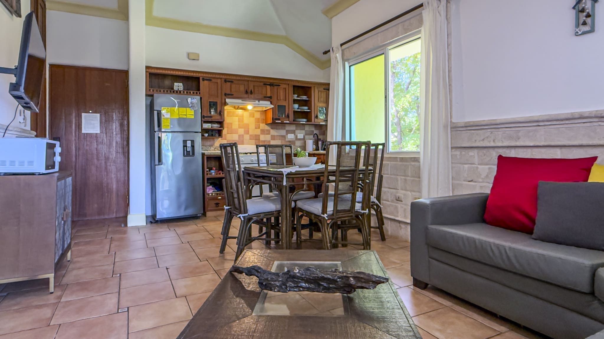buyDRproperty Cozy dining area and kitchen with stainless steel refrigerator and wooden furniture. Sosua Real Estate