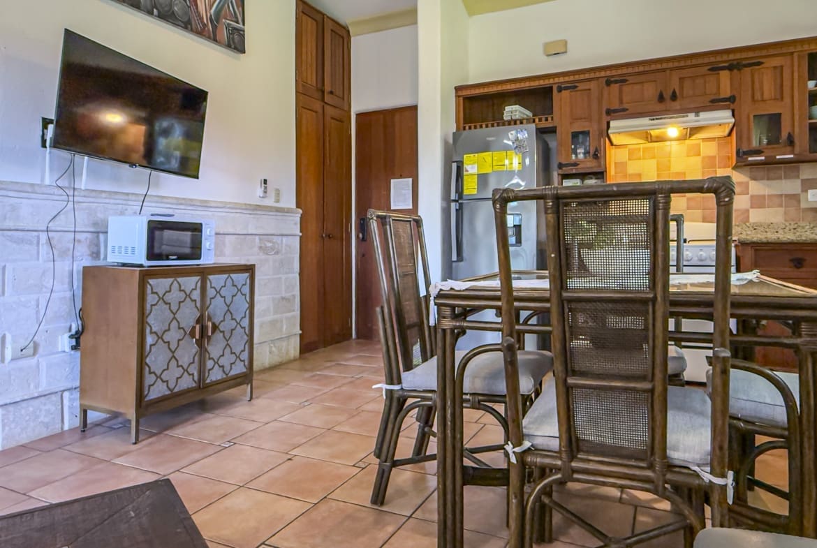 buyDRproperty Dining area with wicker chairs and table, kitchen with wooden cabinets, and a microwave. Sosua Real Estate