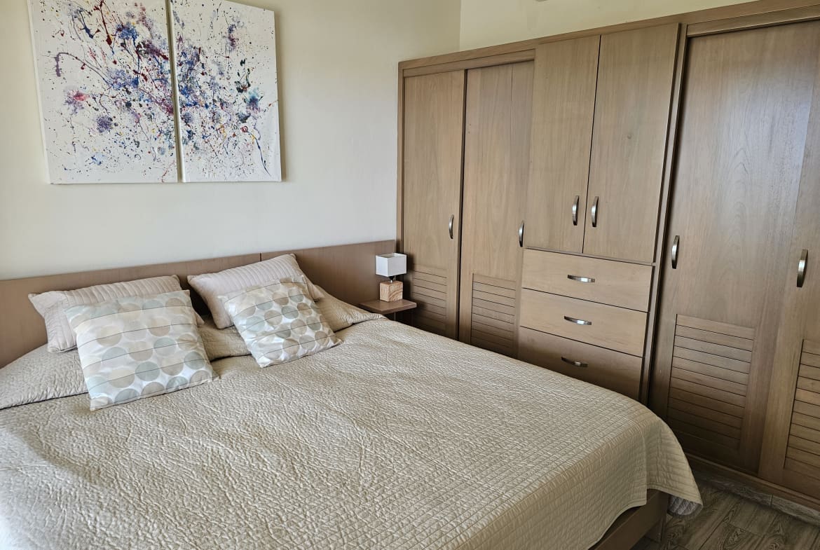 buyDRproperty Modern bedroom with queen bed, wooden wardrobe, and abstract art Sosua Real Estate