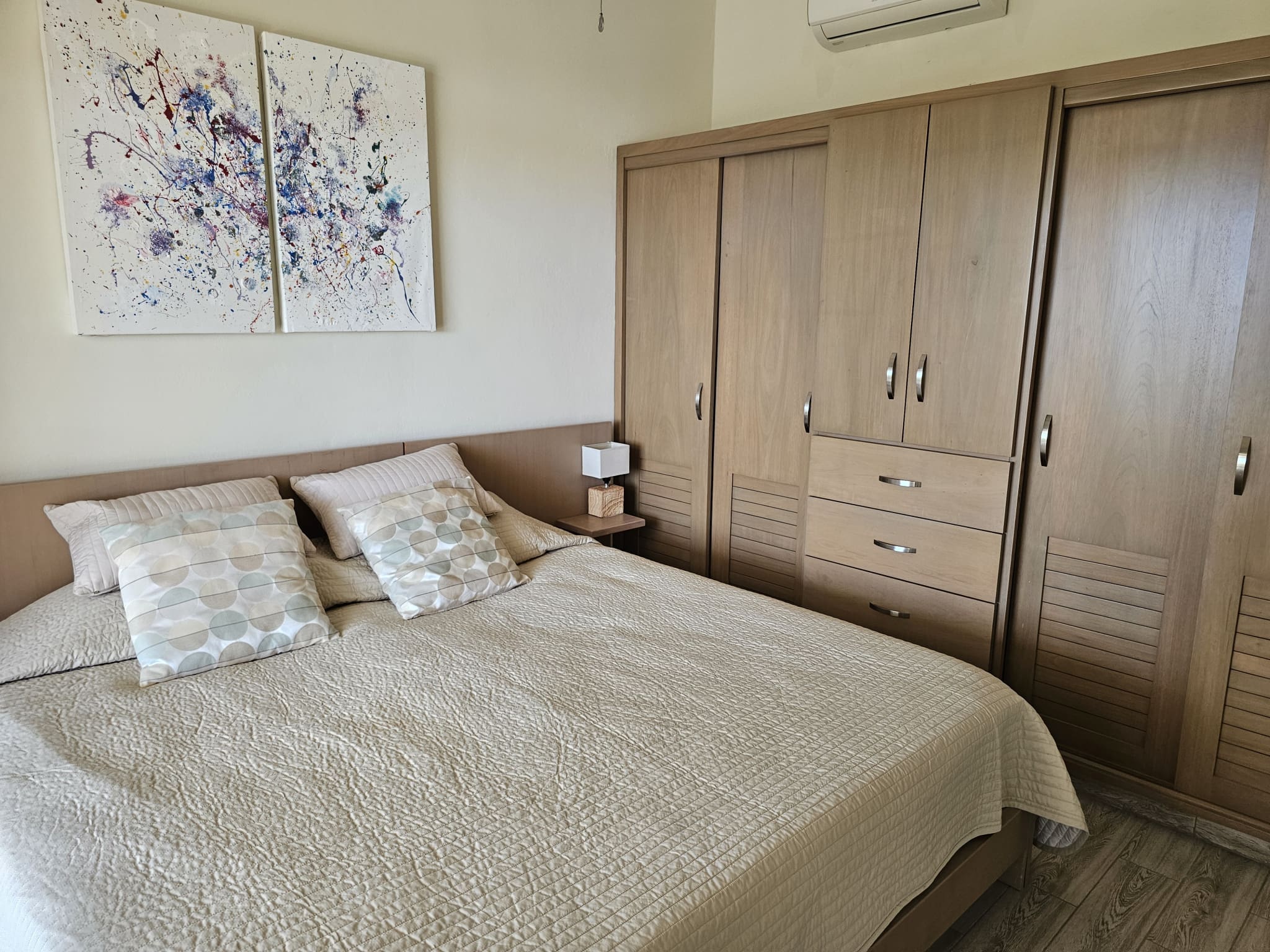 buyDRproperty Modern bedroom with queen bed, wooden wardrobe, and abstract art Sosua Real Estate