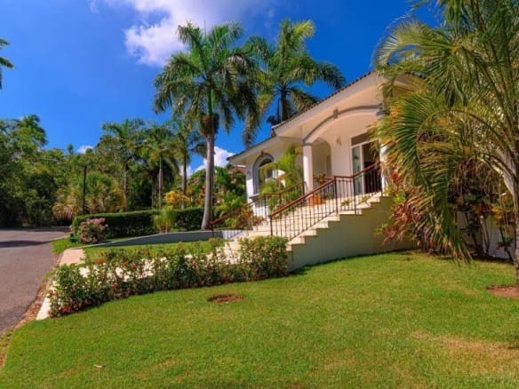 buyDRproperty Luxury villa with palm trees and lush green lawn in a tropical setting. Sosua Real Estate