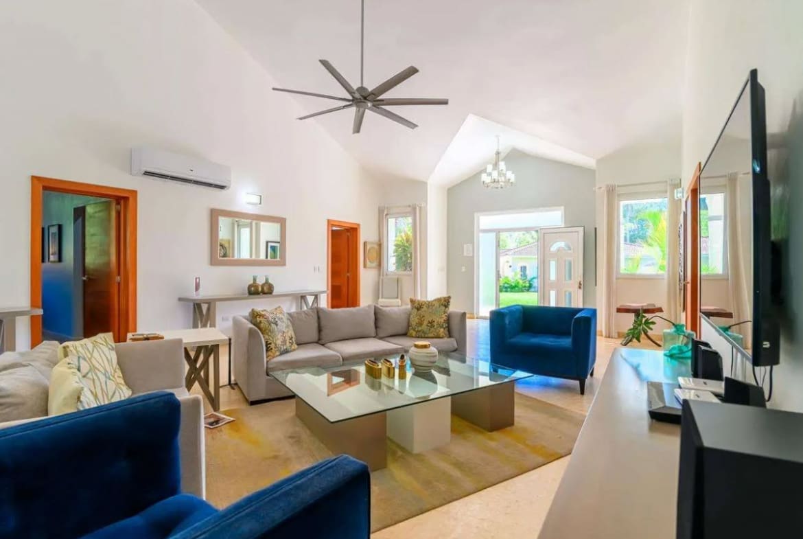 buyDRproperty Spacious living room with modern furniture, ceiling fan, and large windows. Sosua Real Estate