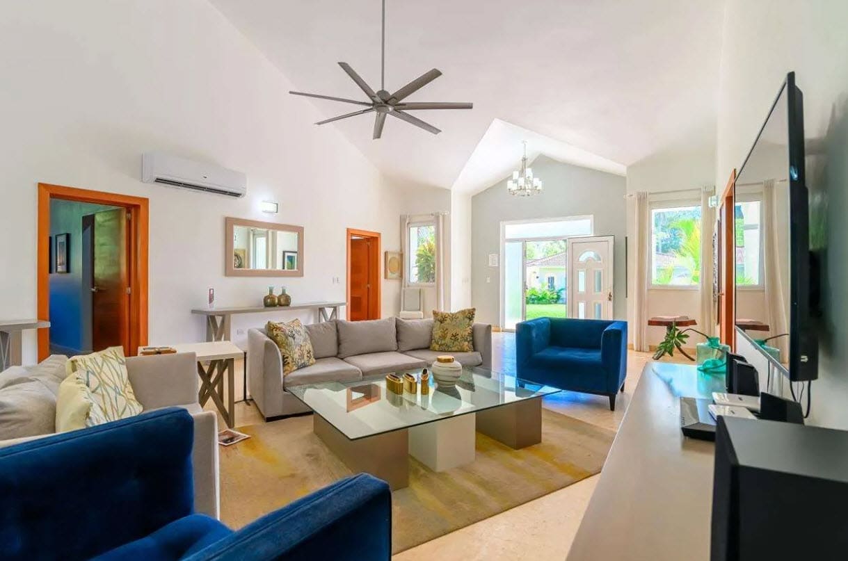 buyDRproperty Spacious living room with modern furniture, ceiling fan, and large windows. Sosua Real Estate