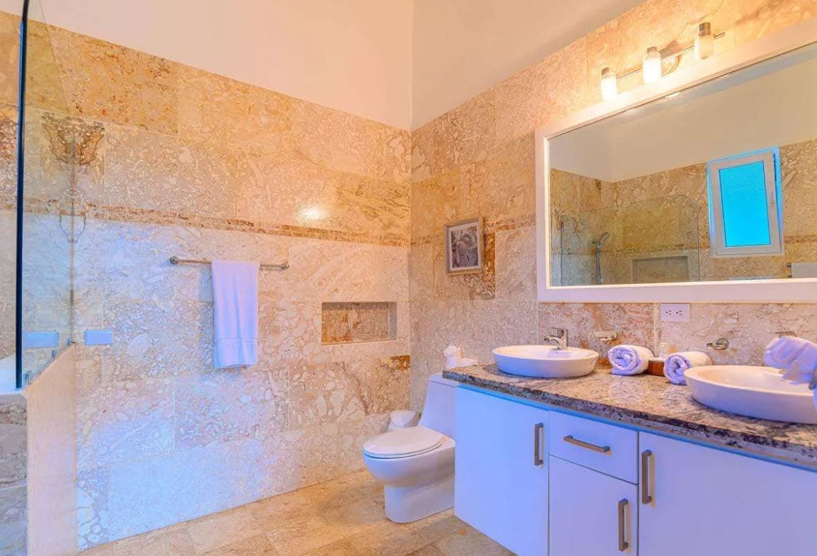 buyDRproperty Luxurious bathroom with marble tiles, dual sinks, and modern fixtures. Sosua Real Estate