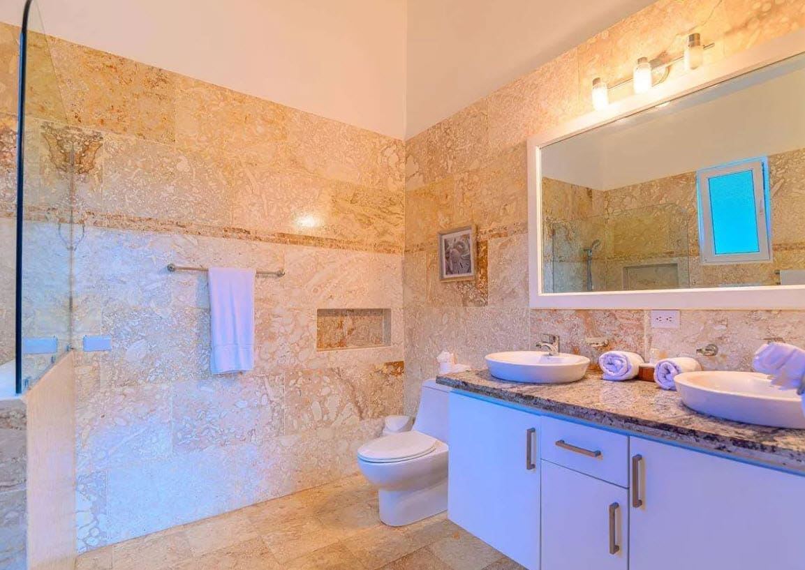 buyDRproperty Luxurious bathroom with marble tiles, dual sinks, and modern fixtures. Sosua Real Estate