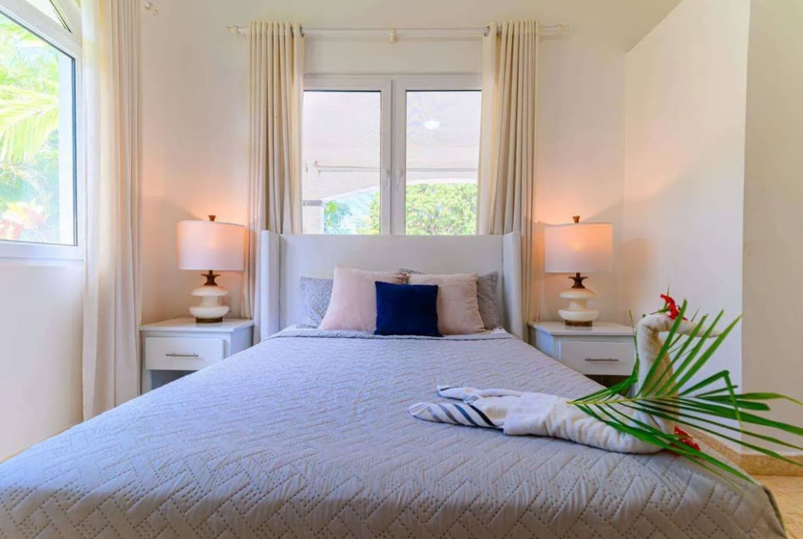 buyDRproperty Serene bedroom with king-size bed, white bedding, and bedside lamps. Sosua Real Estate