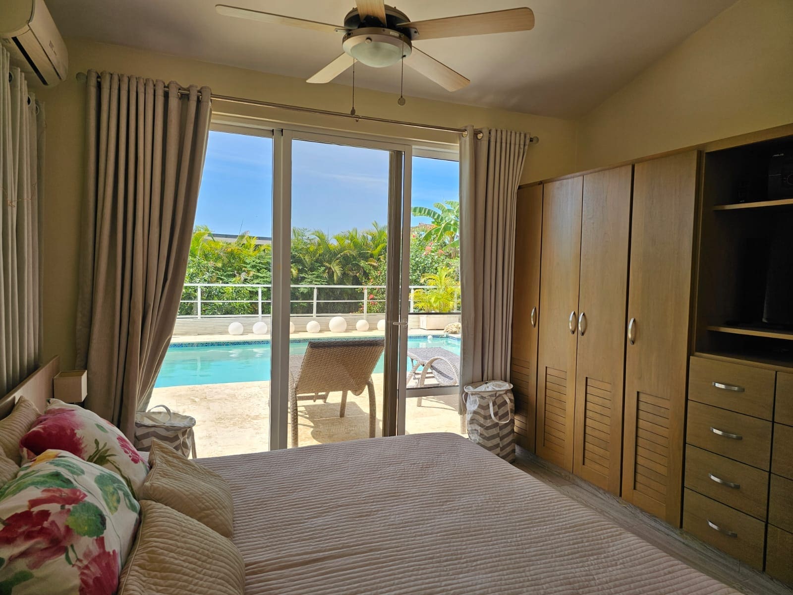 buyDRproperty Bedroom with tropical pool view, ceiling fan, and wooden wardrobe Sosua Real Estate