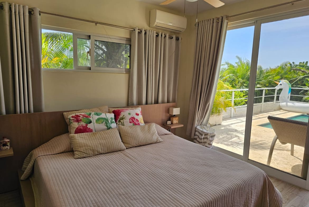 buyDRproperty Bedroom with tropical view and pool access, featuring a king-size bed. Sosua Real Estate