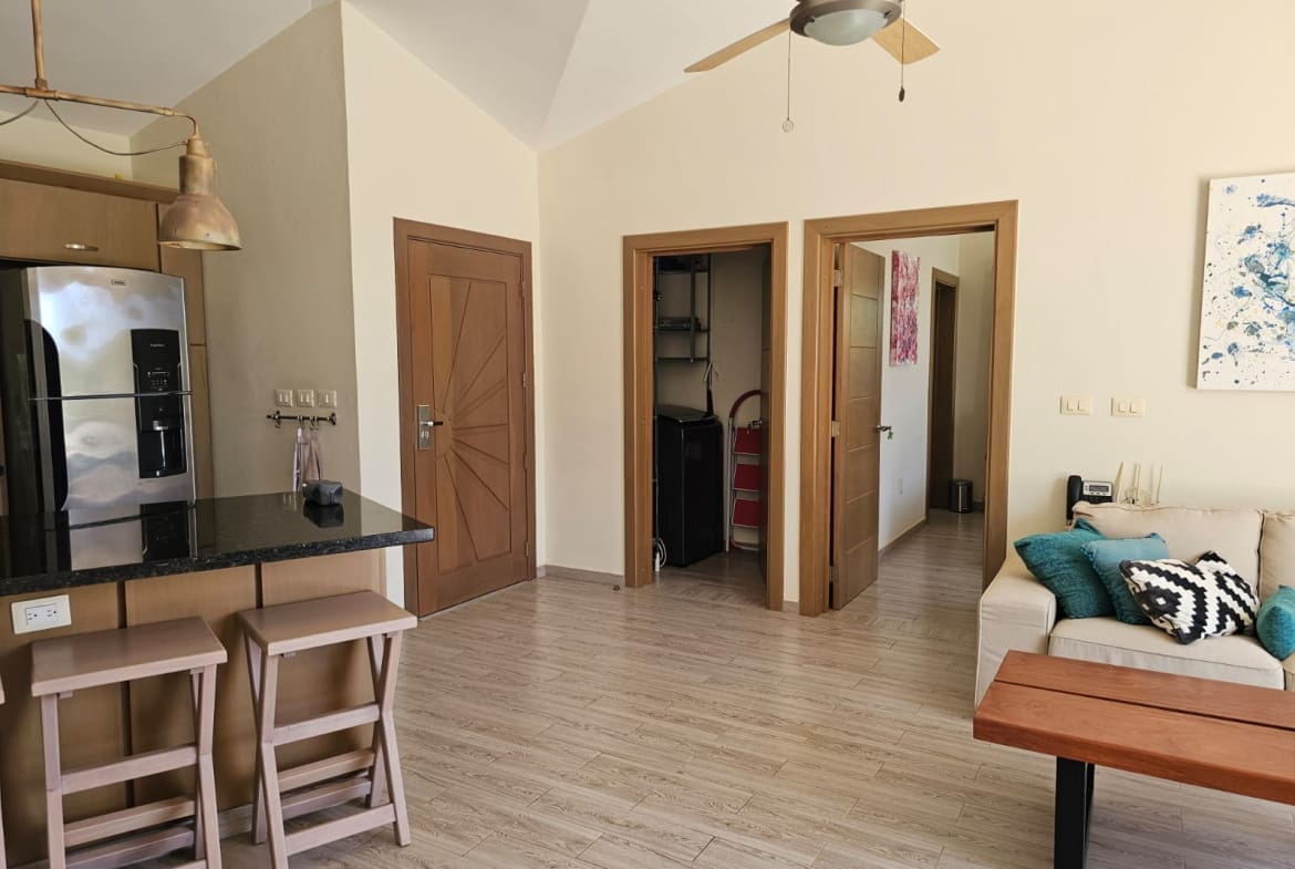buyDRproperty Modern kitchen with island, stools, and living area with sofa and coffee table Sosua Real Estate