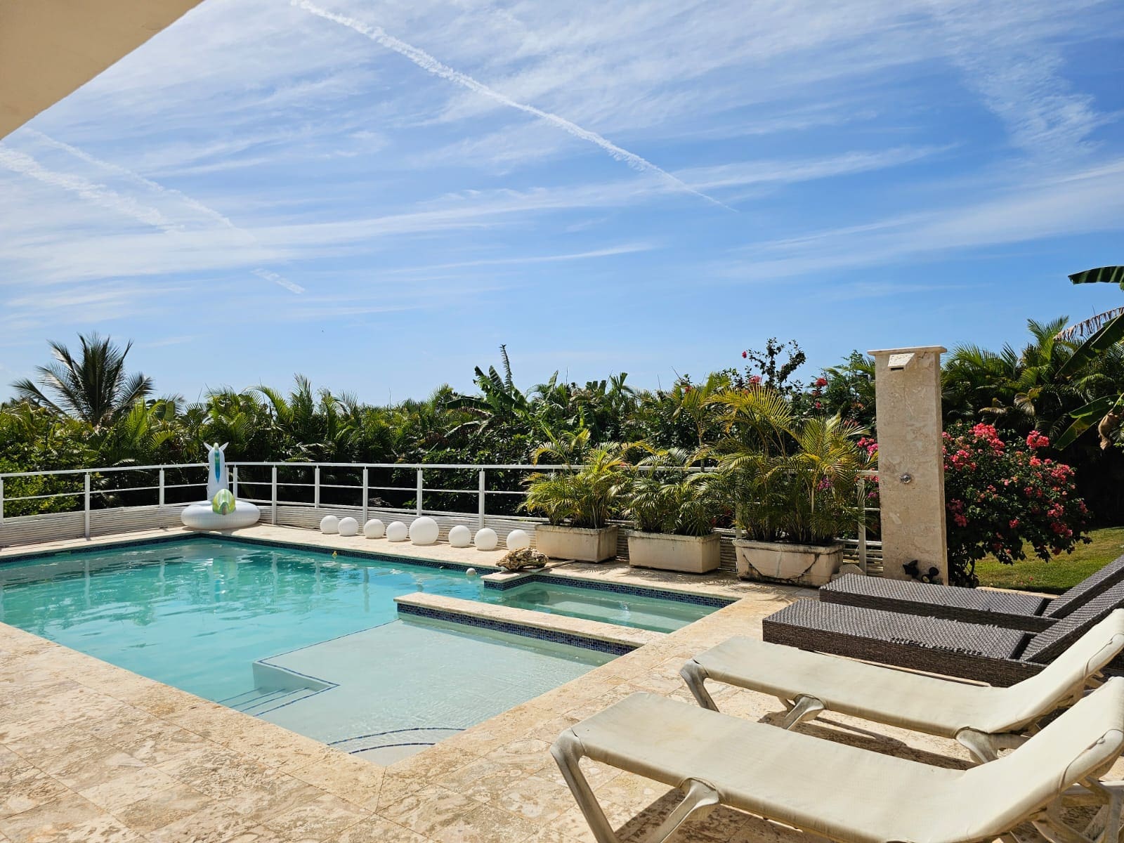 buyDRproperty Luxury villa pool with lounge chairs and tropical foliage under a blue sky. Sosua Real Estate