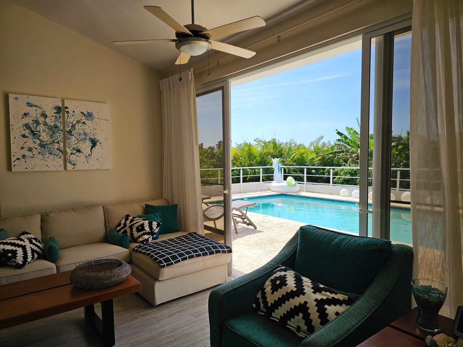 buyDRproperty Living room with sofa and armchair opens to a tropical pool patio with a unicorn float. Sosua Real Estate
