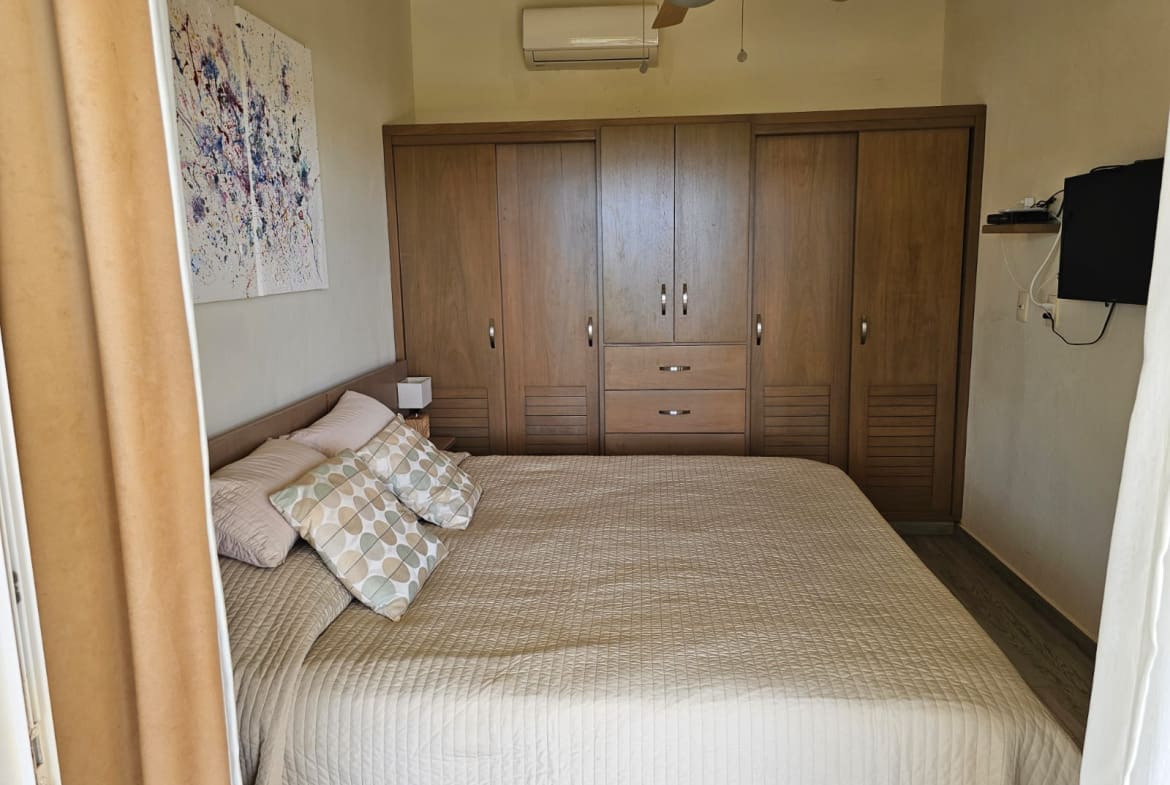 buyDRproperty Spacious bedroom with a large wooden wardrobe and a queen-size bed. Sosua Real Estate