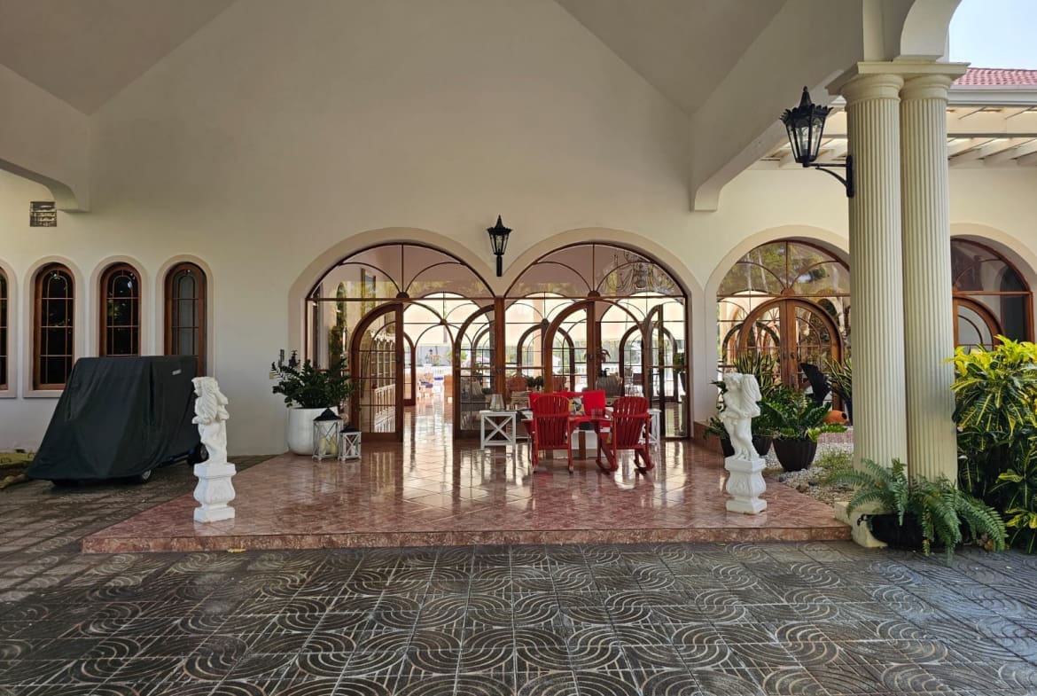 buyDRproperty Elegant arched doorways and windows of a covered patio with outdoor seating. Sosua Real Estate