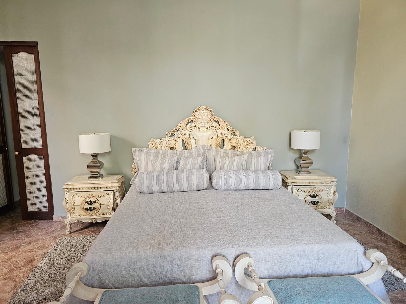 buyDRproperty Luxurious bedroom with a king-size bed, ornate headboard, matching nightstands, and lamps. Sosua Real Estate