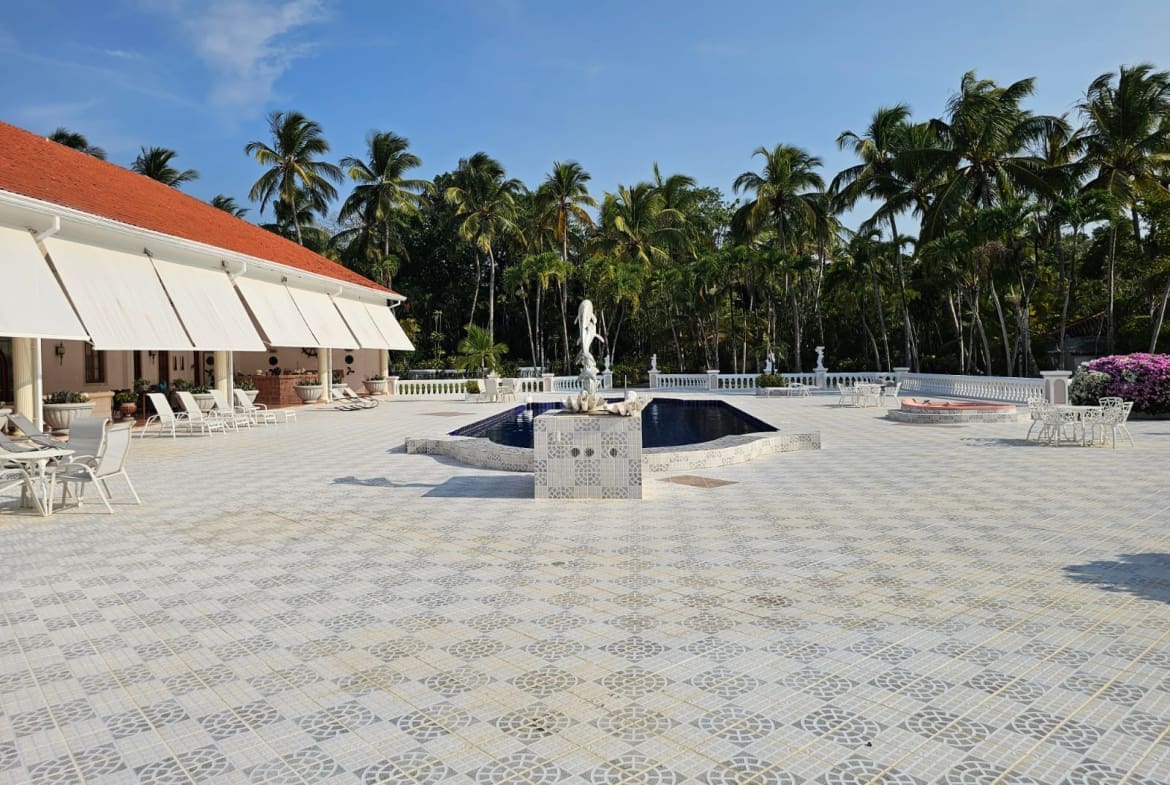 buyDRproperty Luxury resort courtyard with fountain, palm trees, and white tiled patio. Sosua Real Estate