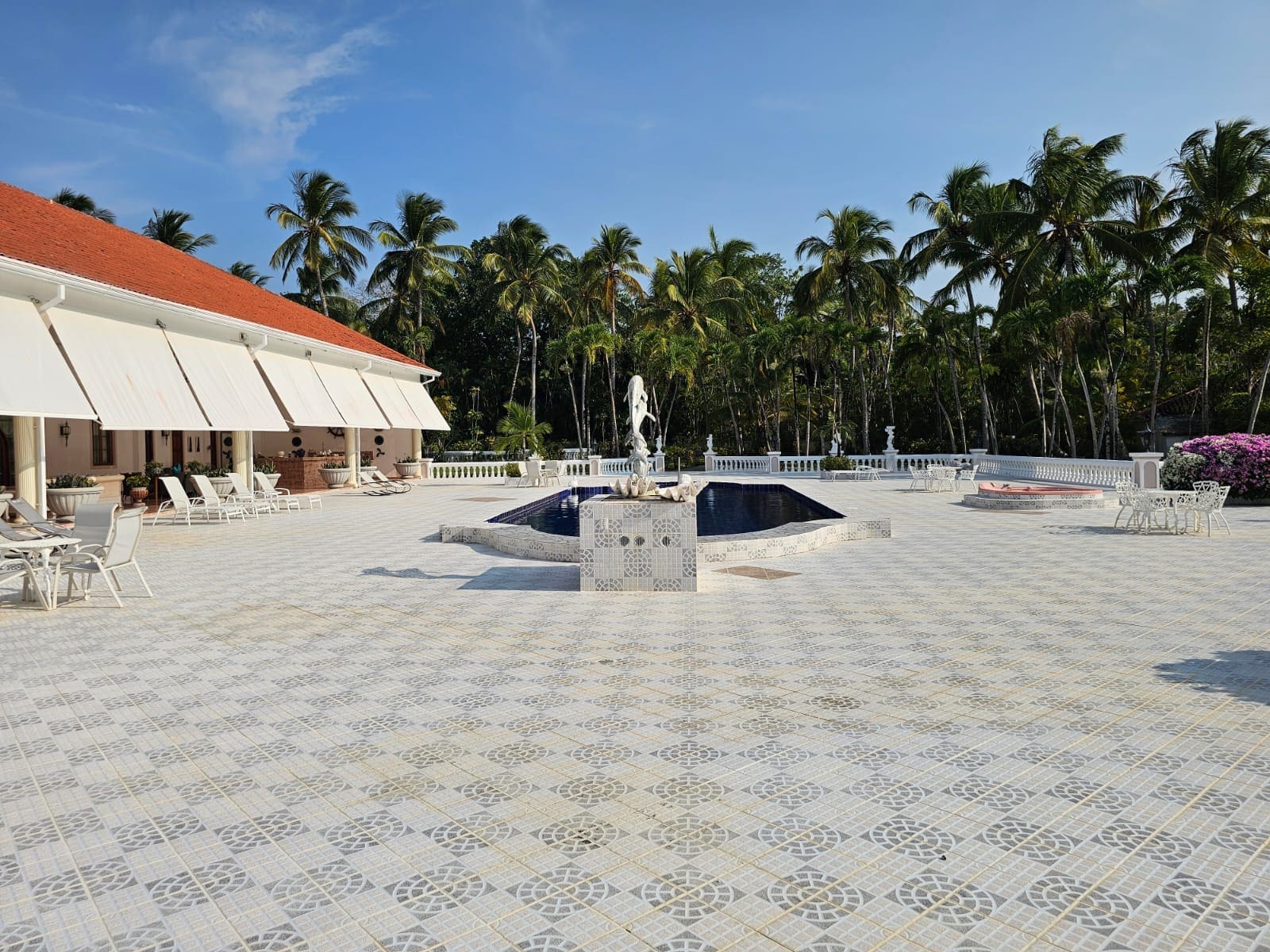 buyDRproperty Luxury resort courtyard with fountain, palm trees, and white tiled patio. Sosua Real Estate