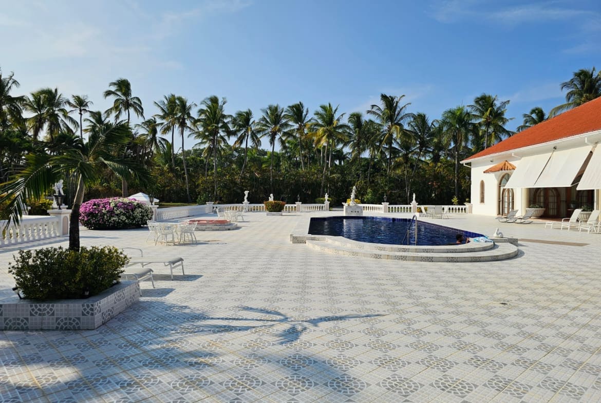 buyDRproperty Luxury villa patio with pool, palm trees, and white tiled flooring. Sosua Real Estate