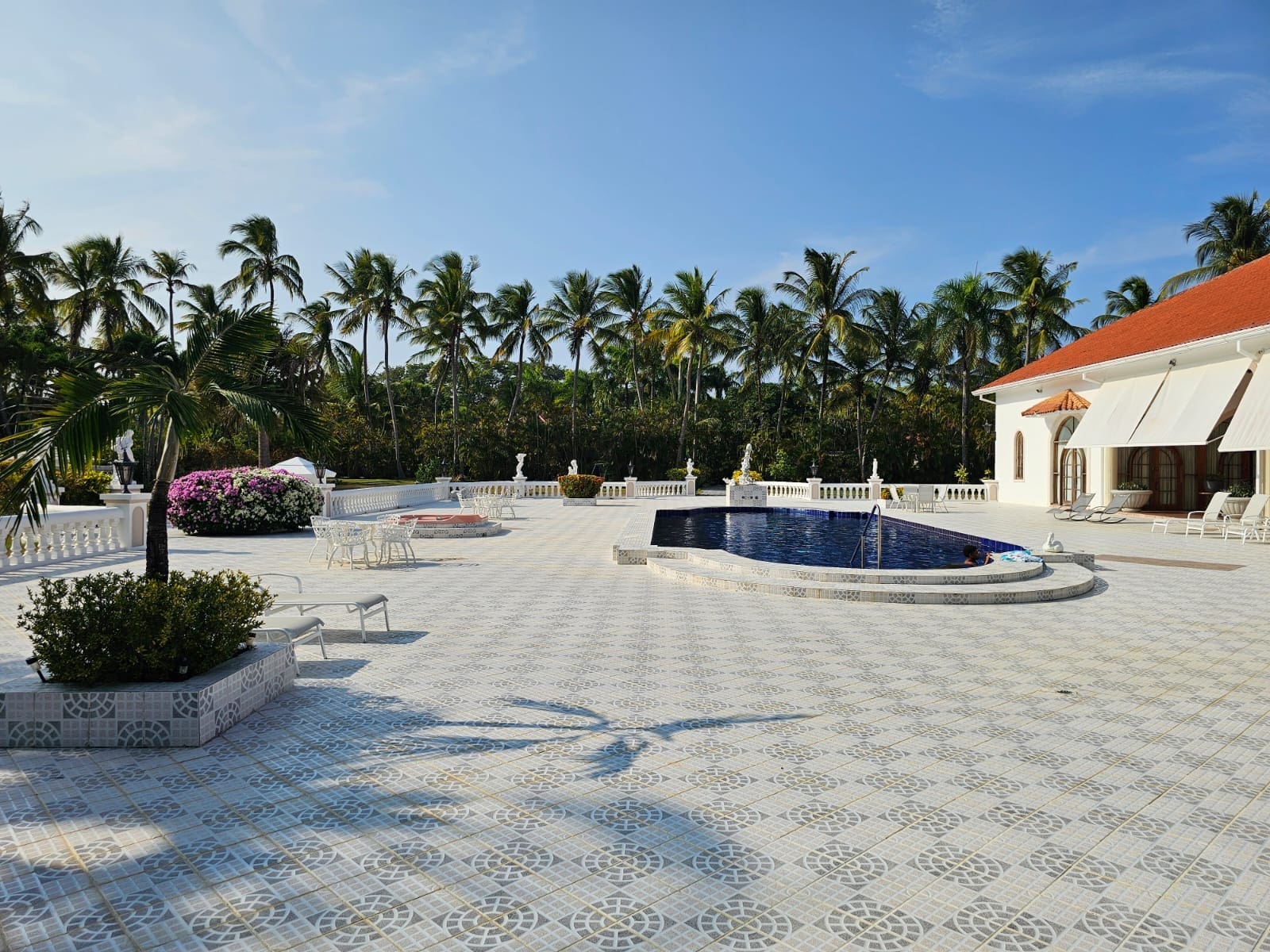 buyDRproperty Luxury villa patio with pool, palm trees, and white tiled flooring. Sosua Real Estate