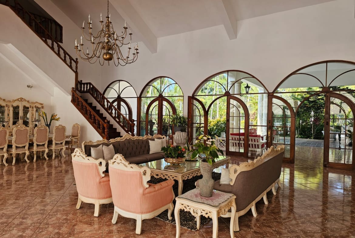 buyDRproperty Luxurious living room with arched windows, ornate furniture, and a grand staircase. Sosua Real Estate