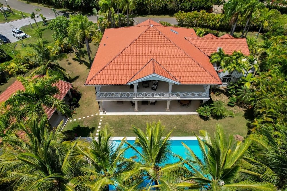 buyDRproperty Aerial view of a luxury villa with a red tile roof, swimming pool, and lush palm trees. Sosua Real Estate