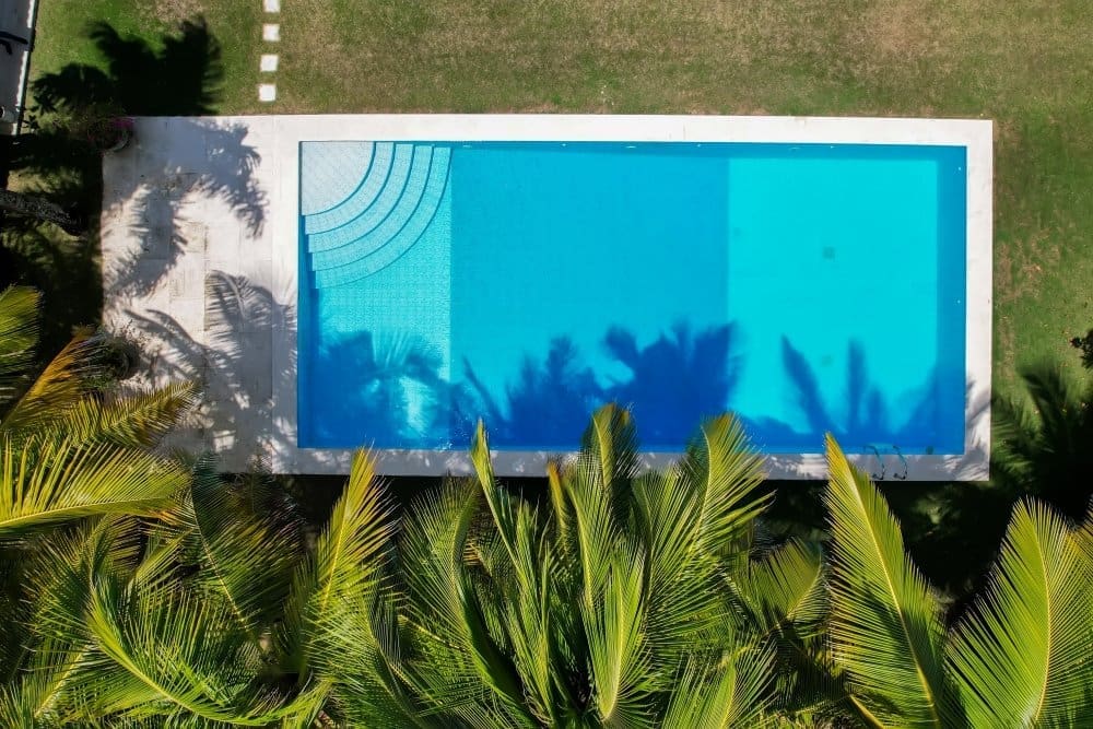 buyDRproperty Aerial view of a rectangular swimming pool with steps, surrounded by palm trees. Sosua Real Estate